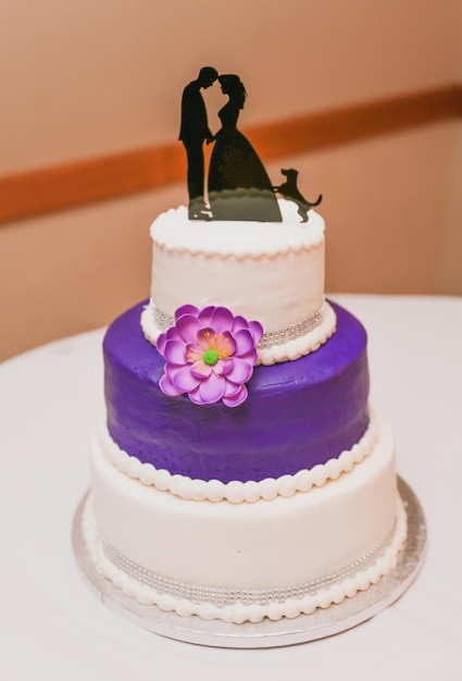 Um bolo de casamento roxo com um casal em cima