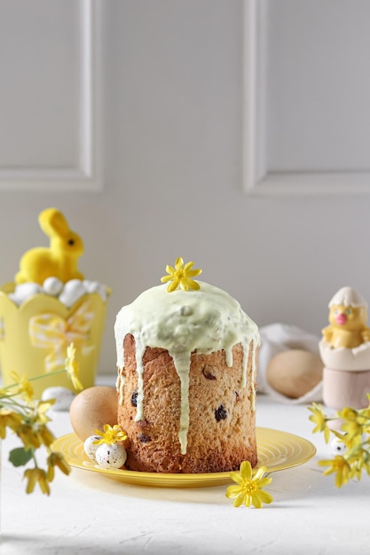 Um bolo de páscoa com cobertura amarela e um coelhinho amarelo por cima.