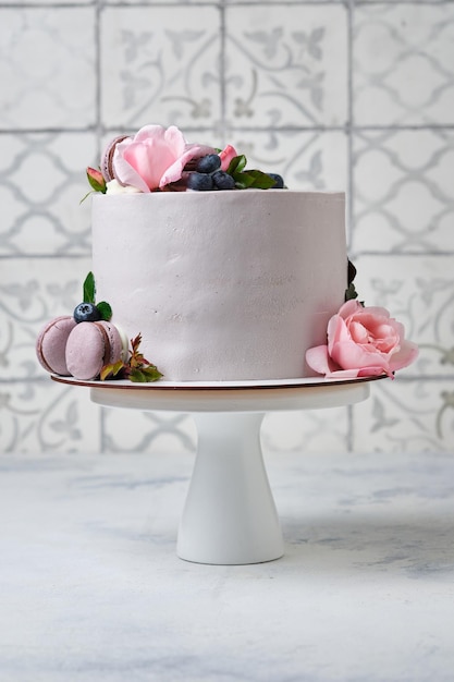 Um bolo lindo e delicado para uma menina. a sobremesa é decorada com mirtilos frescos, rosas e bolos de macarons.