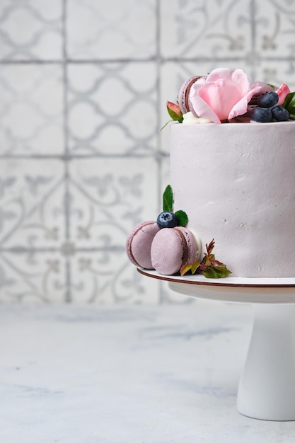 Foto um bolo lindo e delicado para uma menina. a sobremesa é decorada com mirtilos frescos, rosas e bolos de macarons.