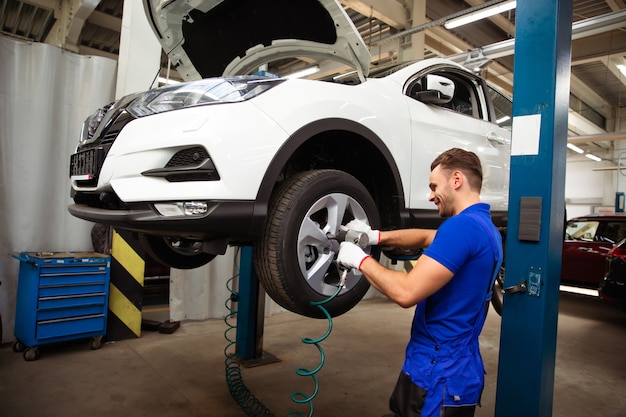 Um bom mecânico de automóveis profissional troca a roda de um carro ou realiza uma troca de pneus em uma oficina especializada