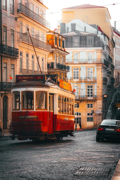 Um bonde vermelho está em uma rua em Lisboa.