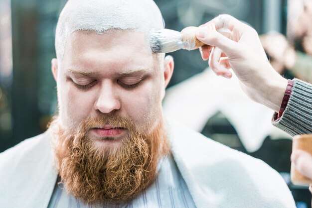 Um bonito com barba ruiva e pincel de barbear perto de sua cabeça