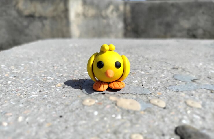 Foto um bonito pássaro de plástico de barro amarelo feito à mão minimalista em pedra feito com brinquedo de barro de massa