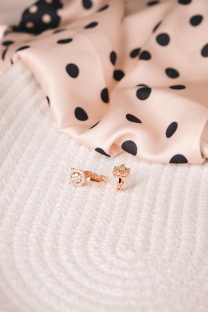 Um brinco de ouro está em um vestido de bolinhas rosa.