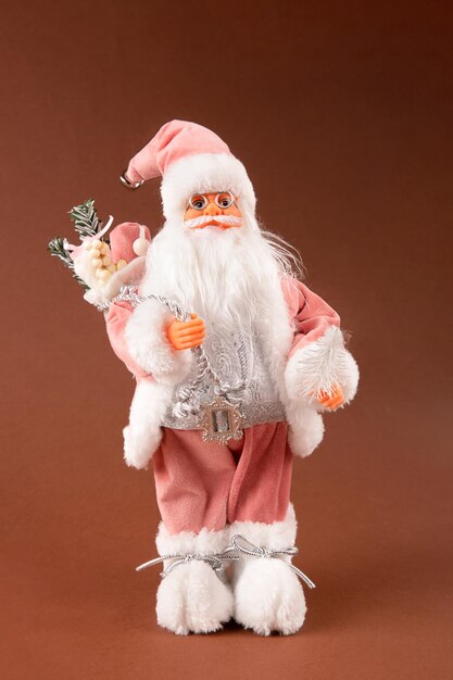Foto um brinquedo engraçado de papai noel com um saco de presentes nas costas e uma árvore de natal na mão e calças cor-de-rosa