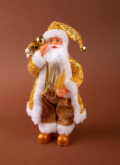 Um brinquedo engraçado de papai noel com um saco de presentes nas costas e uma árvore de natal na mão e calças douradas