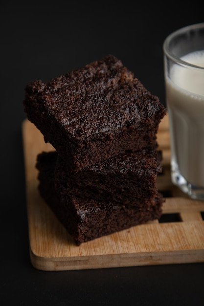 Um brownie com chocolate ao lado está ao lado de um copo de leite