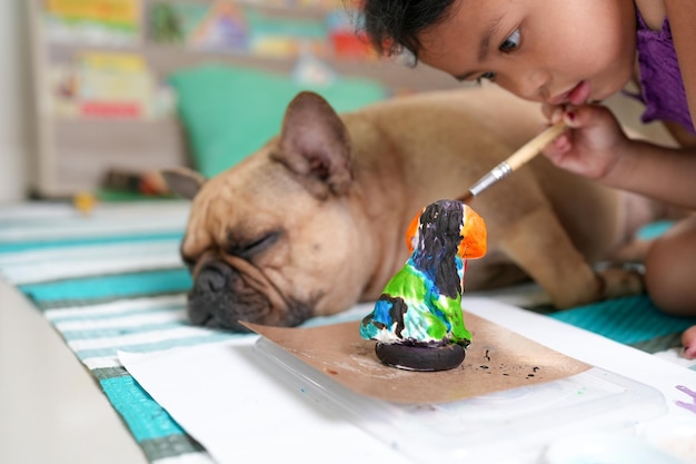 Um buldogue francês está pintando um pato em um prato.