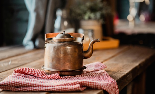 Um bule de metal de cobre quente vintage fica sobre uma mesa de madeira Cozinha moderna e estilosa