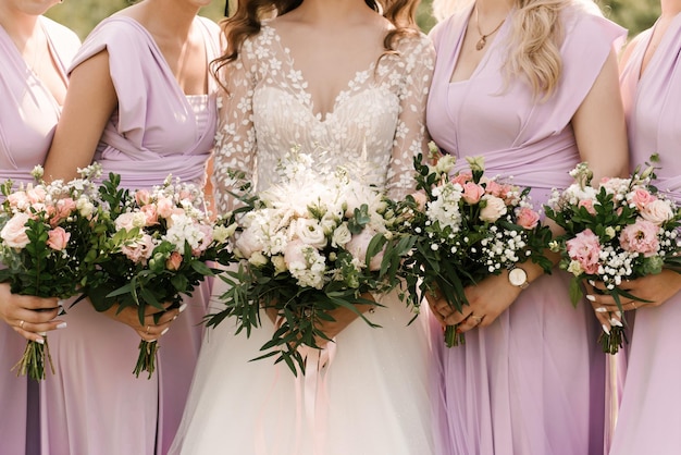 Um buquê de casamento luxuoso com peônias brancas e rosa nas mãos da noiva e dama de honra com buquês
