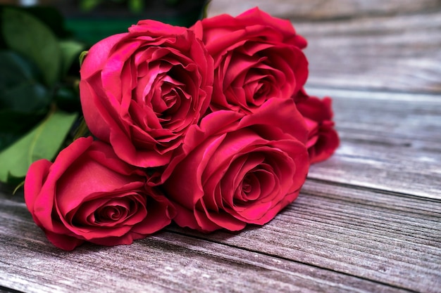 Um buquê de cinco rosas vermelhas em uma superfície de madeira