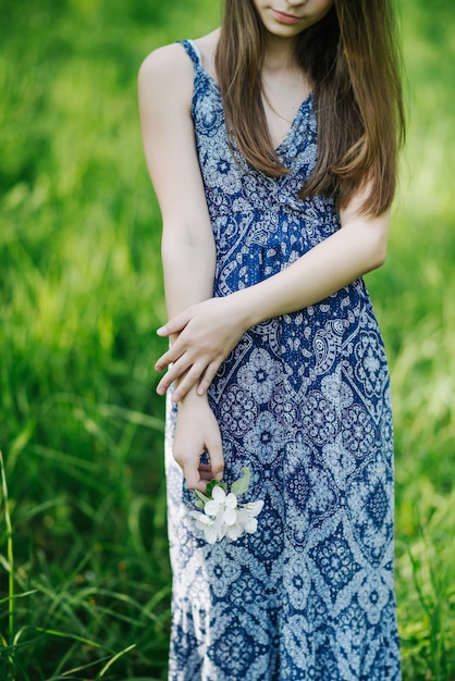 Um buquê de flores da primavera nas mãos de uma menina de vestido azul. Macieira florescendo no parque na primavera. Foco suave. Fechar-se.