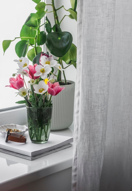 Um buquê de flores do jardim da primavera uma flor caseira em uma panela revistas no parapeito da janela na sala de estar Casa aconchegante interior