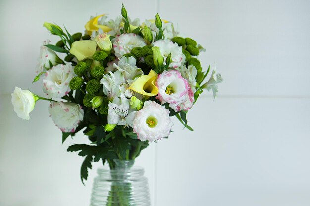 Um buquê de flores em um vaso com folhas verdes e flores brancas.