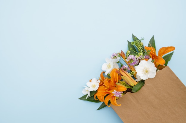 Um buquê de flores em uma bolsa de artesanato em um fundo azul