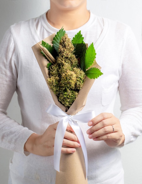 Foto um buquê de flores frescas de cannabis na mão de uma mulher