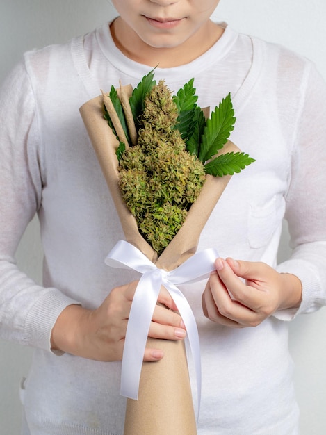 Foto um buquê de flores frescas de cannabis na mão de uma mulher