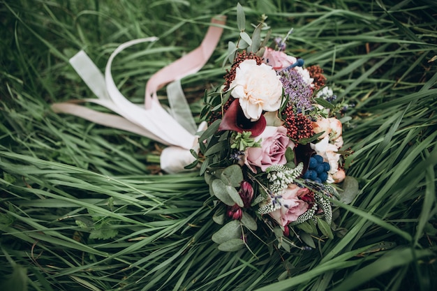 Um buquê de flores vermelhas, frutos pretos e verdes. O buquê da noiva