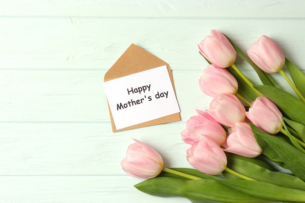 Um buquê de lindas tulipas e um cartão de texto em um fundo de madeira