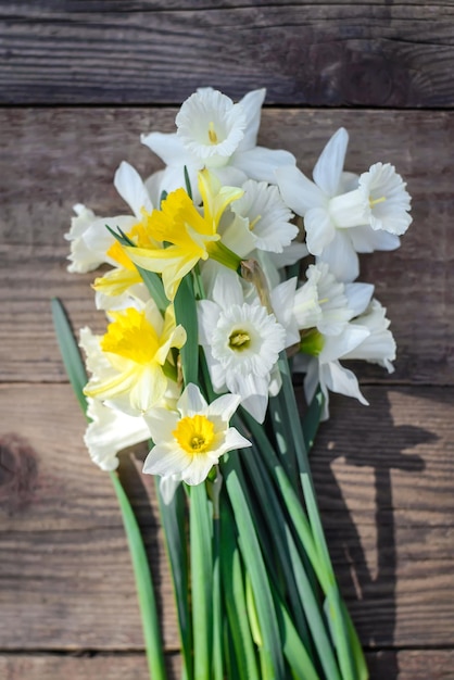 Um buquê de lindos narcisos brancos e amarelos sobre um fundo de madeira rústico fecha