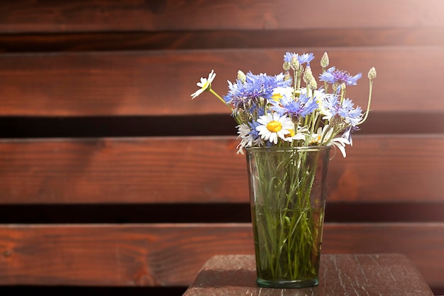 Um buquê de margaridas e flores em um vaso de vidro ao sol