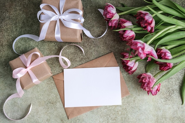 Um buquê de presentes de tulipas e um cartão de papel branco em branco simulado para texto plano, local de vista superior para te
