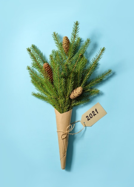 Um buquê de ramos de abeto com cones embrulhados em papel artesanal com etiqueta 2021.