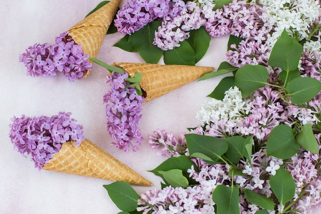 Foto um buquê de rosa lilás e branco lilás, três cones de bolacha com lilás