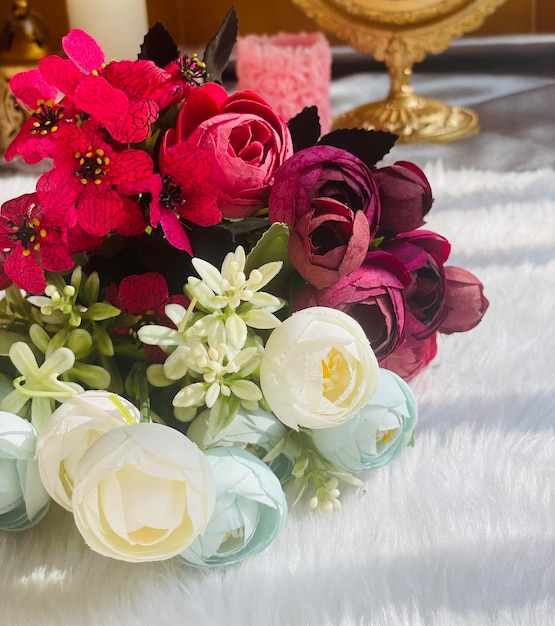 Um buquê de rosas e outras flores estão sobre um cobertor branco.