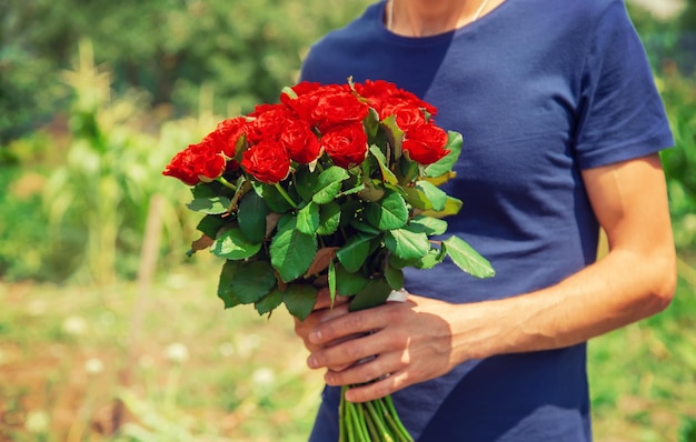 Um buquê de rosas vermelhas nas mãos de um homem foco seletivo