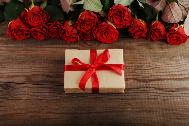 Um buquê de rosas vermelhas, um presente na mesa de madeira