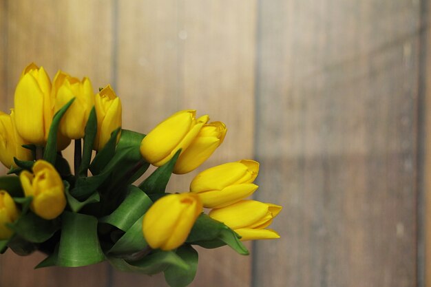 Um buquê de tulipas amarelas em um vaso no chão. Um presente para o dia da mulher de flores de tulipa amarela. Lindas flores amarelas em um vaso por parede.