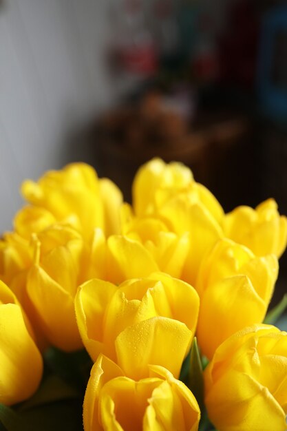 Um buquê de tulipas amarelas frescas em um vaso em uma mesa perto da janela