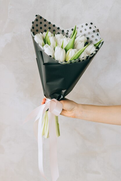 Foto um buquê de tulipas brancas em uma embalagem preta