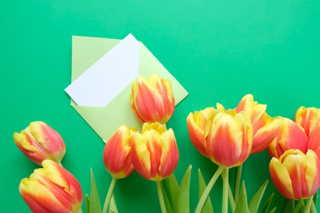 Um buquê de tulipas e um envelope com uma nota sobre um fundo verde. conceito de dia internacional da mulher, dia das mães, páscoa