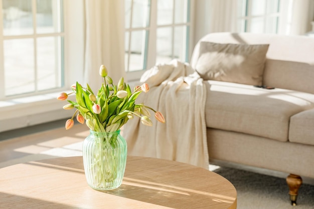 Um buquê de tulipas em um lindo vaso em casa em um interior moderno e brilhante em uma mesa de madeira