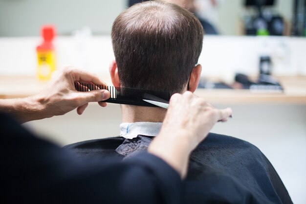 Foto um cabeleireiro profissional usando máscara protetora cortando o cabelo de uma cliente durante o coronavírus