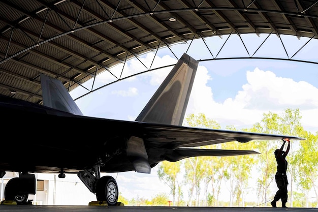 Um caça a jato preto está estacionado em um hangar com a cauda visível.