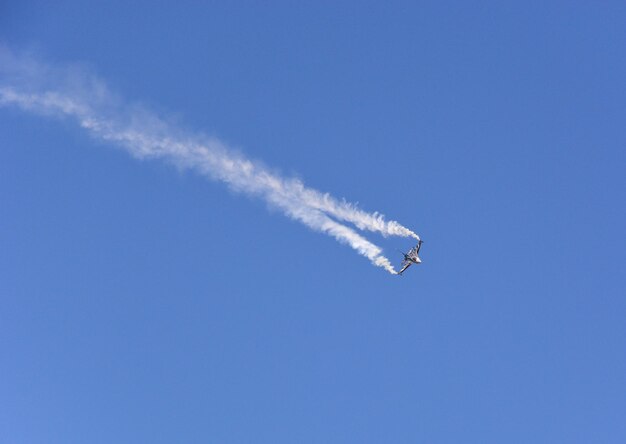 Um caça militar está voando no céu azul