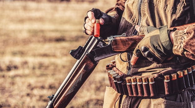 Um caçador com uma arma de caça e forma de caça para caçar em uma floresta de outono. o homem está caçando. homem caçador. período de caça, temporada de outono. homem com uma arma.