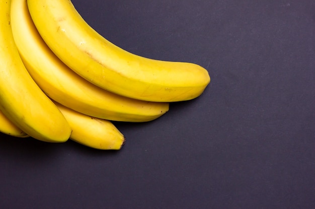 Um cacho de bananas em um fundo preto Um buquê de bananas em close up