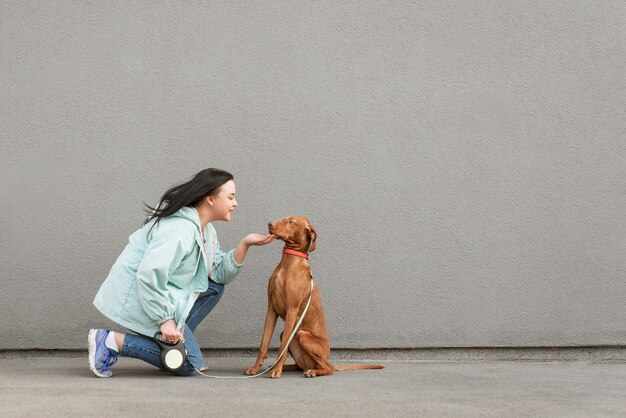 Um cachorro marrom brincalhão e uma garota feliz sentados