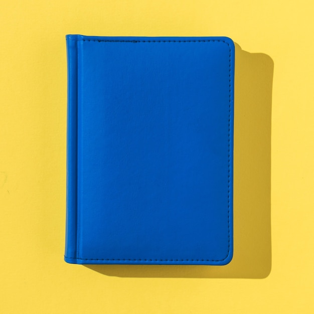 Foto um caderno azul em uma luz brilhante sobre um fundo amarelo. acessórios de escritório.