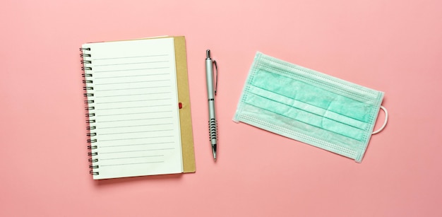 Foto um caderno, caneta e máscara protetora