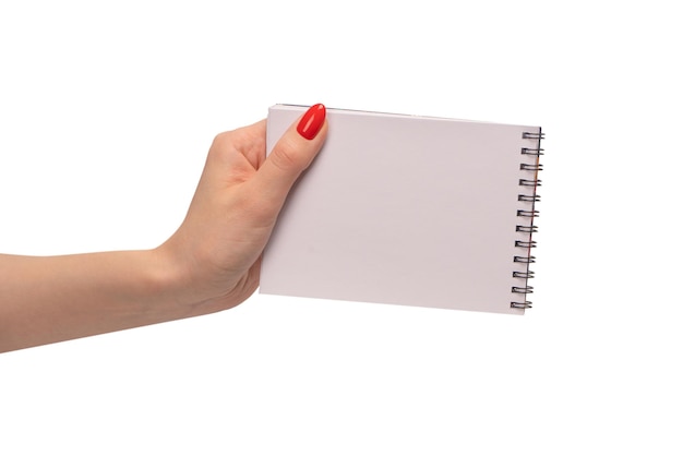 Um caderno com papel branco vazio nas mãos da mulher com unhas vermelhas