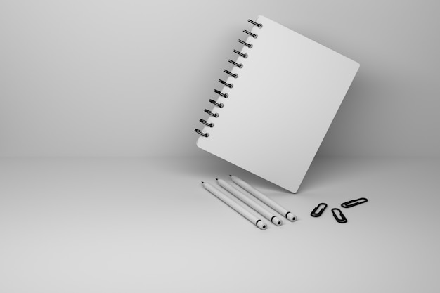 Um caderno espiral com capa em branco e três lápis