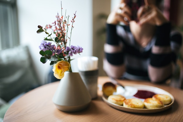 Um café da manhã aconchegante em cores brilhantes. Vaso com flores, cheesecake