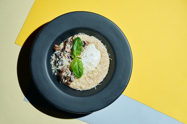 Um café da manhã delicioso e saudável. Aveia com ovo escalfado, parmesão e cogumelos em uma placa preta em s