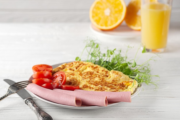 Um café da manhã leve de omeletes francesas com tomates de salsicha e microgreens Café da manhã europeu